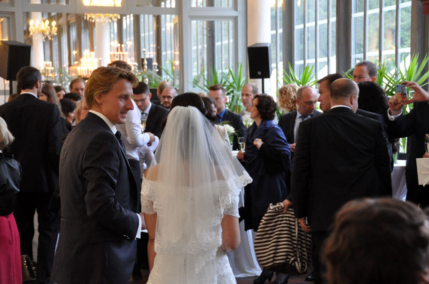 Gut gelaunte Gäste und ein entspanntes Hochzeitspaar beim Sektempfang